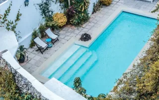 Piscina construida con gunitado en un patio interior, rodeada de vegetación y acabados personalizados