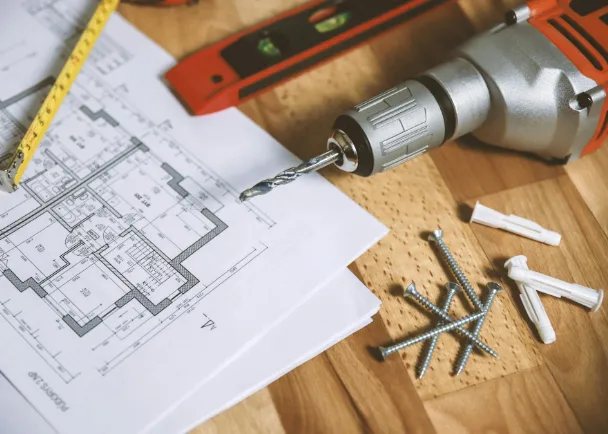 Herramientas eléctricas para construcción con taladro y planos de obra